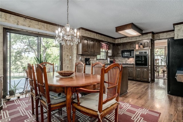 dining space with ornamental molding, a chandelier, a textured ceiling, and dark hardwood / wood-style flooring