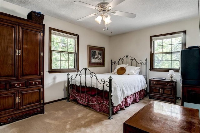 bedroom with light carpet, ceiling fan, multiple windows, and a textured ceiling