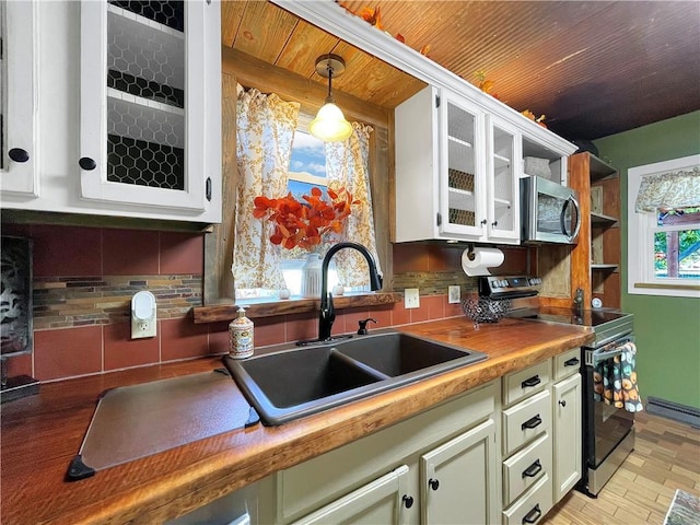 kitchen featuring pendant lighting, green cabinetry, sink, decorative backsplash, and appliances with stainless steel finishes