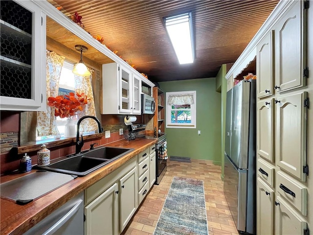 kitchen with white cabinets, sink, decorative light fixtures, stainless steel appliances, and wood counters