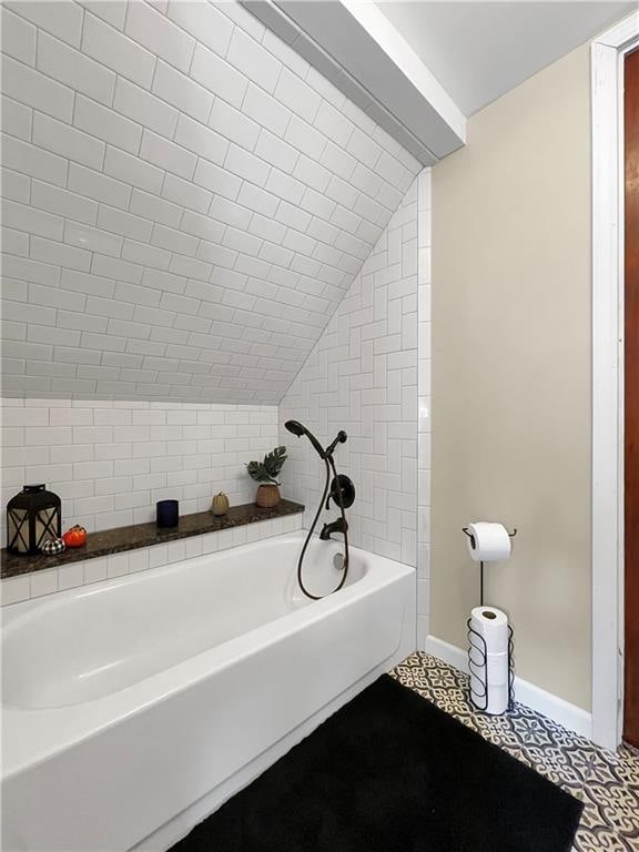 bathroom featuring a bathtub, lofted ceiling, and tile patterned flooring