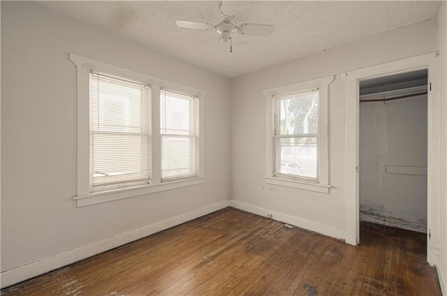 unfurnished bedroom with dark hardwood / wood-style flooring, a closet, multiple windows, and ceiling fan