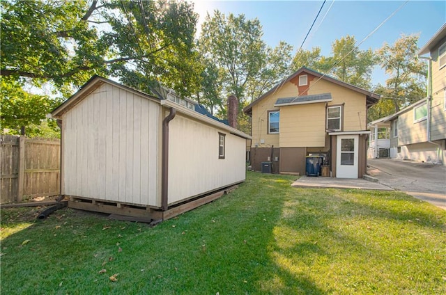 rear view of house with a lawn and a storage shed