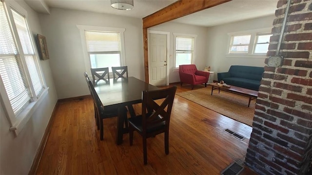 dining space featuring beamed ceiling and wood-type flooring