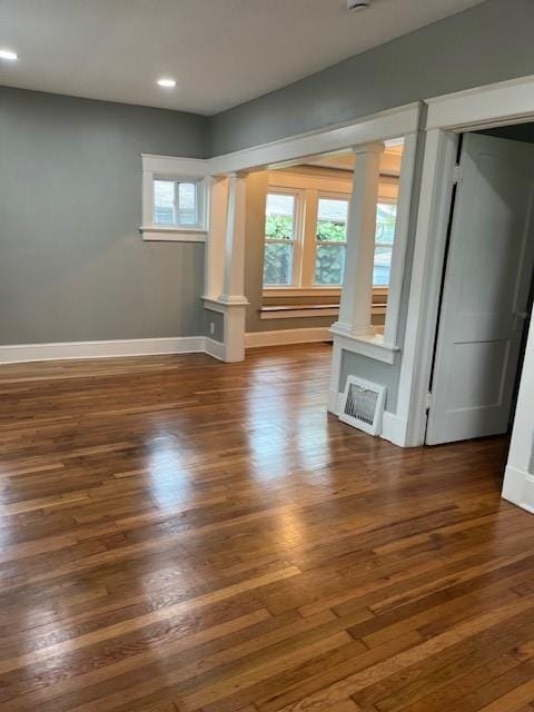 unfurnished living room with dark hardwood / wood-style floors and ornate columns