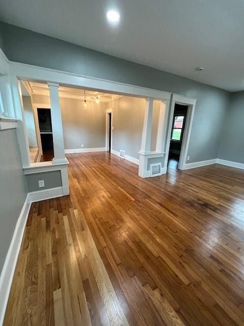 empty room featuring decorative columns and hardwood / wood-style flooring