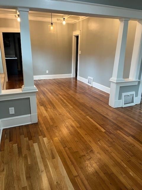 spare room featuring ornate columns, hardwood / wood-style flooring, and ornamental molding