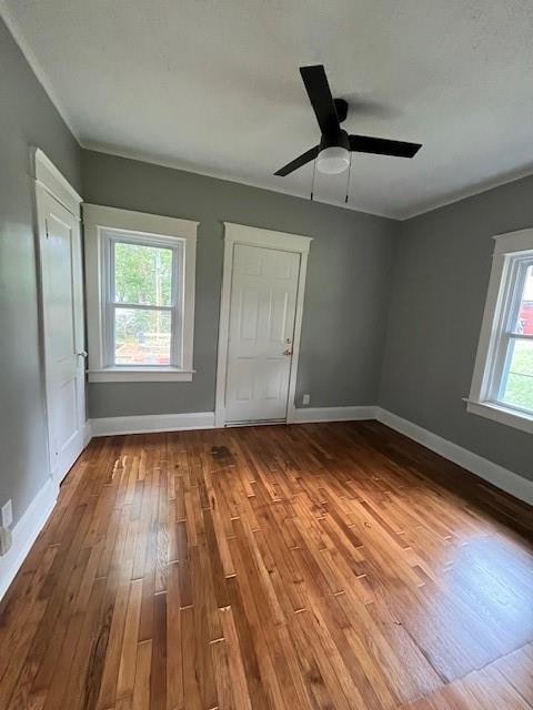 unfurnished bedroom with ceiling fan, crown molding, hardwood / wood-style floors, and multiple windows