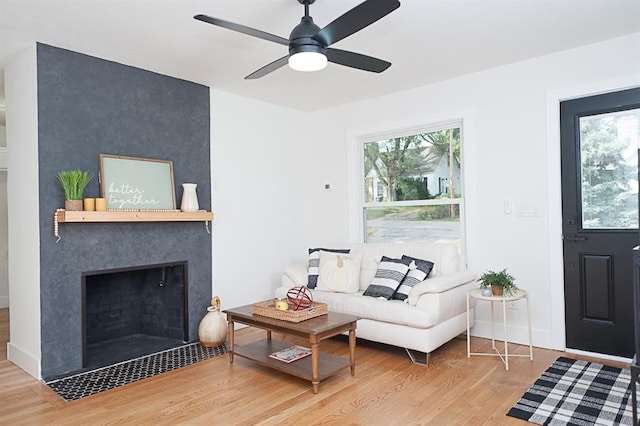 living room with a large fireplace, hardwood / wood-style flooring, plenty of natural light, and ceiling fan