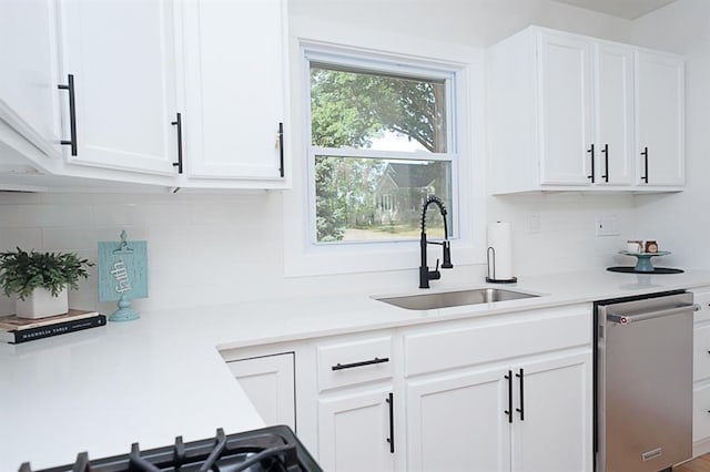 kitchen with white cabinets, stainless steel dishwasher, sink, and tasteful backsplash