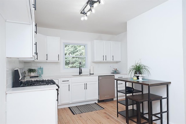 kitchen with white cabinetry, sink, stainless steel appliances, light hardwood / wood-style flooring, and decorative backsplash