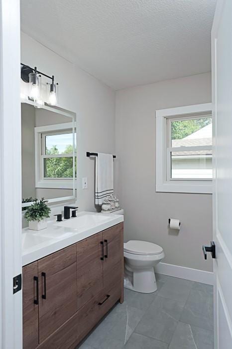 bathroom featuring vanity, a healthy amount of sunlight, toilet, and a textured ceiling