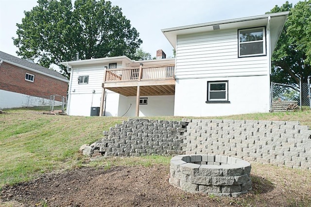 rear view of house featuring a lawn, a deck, and an outdoor fire pit