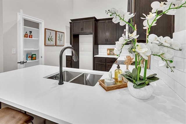 kitchen with backsplash, sink, dark brown cabinets, kitchen peninsula, and a breakfast bar area