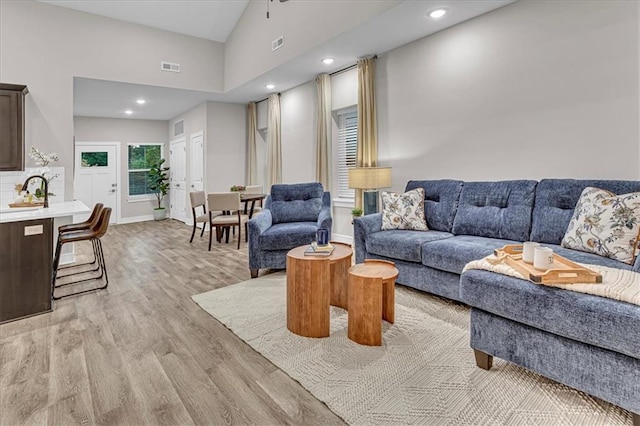 living room with light wood-type flooring and high vaulted ceiling