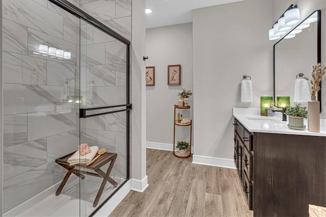 bathroom with wood-type flooring, vanity, and a shower with door