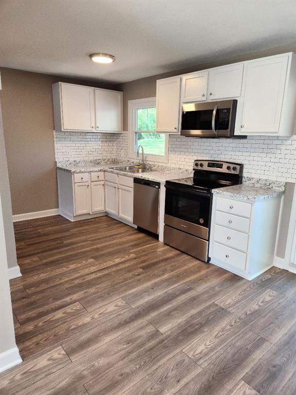 kitchen with white cabinets, hardwood / wood-style flooring, appliances with stainless steel finishes, and sink