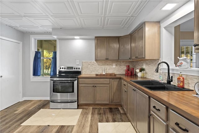 kitchen with electric stove, butcher block counters, dark hardwood / wood-style floors, and a wealth of natural light