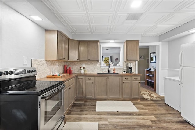 kitchen with sink, dark hardwood / wood-style flooring, white refrigerator, stainless steel electric stove, and decorative backsplash