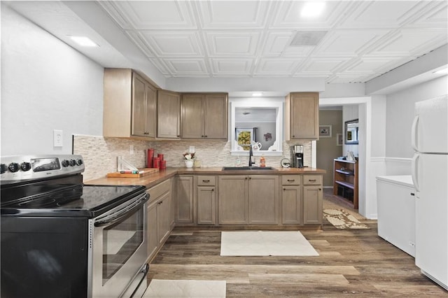 kitchen with freestanding refrigerator, wood finished floors, a sink, backsplash, and stainless steel electric range oven