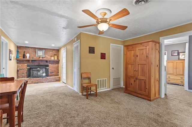 carpeted living area featuring ceiling fan, a fireplace, and visible vents