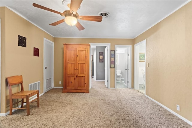 carpeted bedroom with ceiling fan, ornamental molding, and ensuite bath