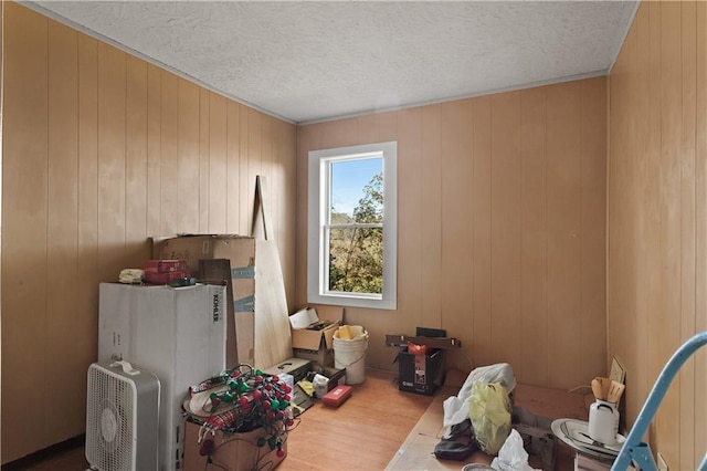 misc room featuring wood walls, a textured ceiling, and wood finished floors