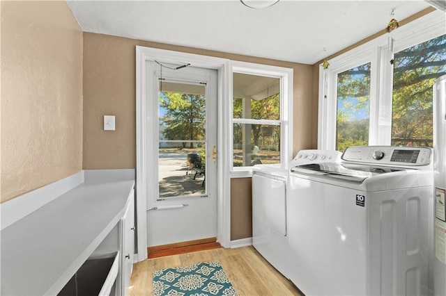 laundry area featuring laundry area, a textured wall, light wood-style floors, baseboards, and independent washer and dryer