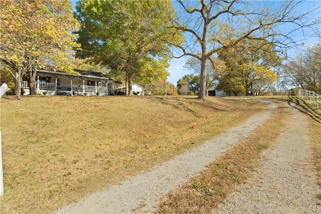 view of yard with dirt driveway and covered porch