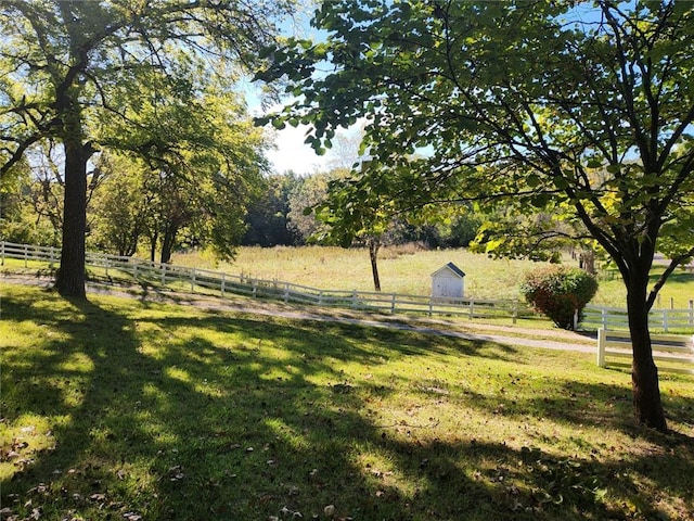 view of yard with a rural view, fence, and an outdoor structure