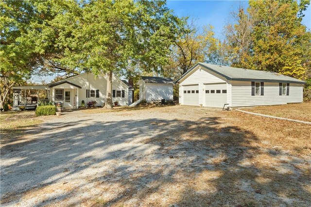 view of front facade featuring dirt driveway, an outdoor structure, and a porch