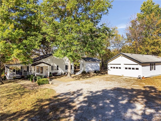 view of front of property featuring a porch, dirt driveway, an outbuilding, a garage, and a shed