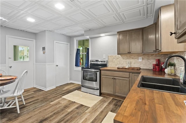 kitchen featuring a sink, dark wood finished floors, wooden counters, electric stove, and tasteful backsplash