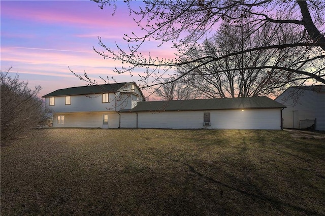 back of house at dusk with a lawn