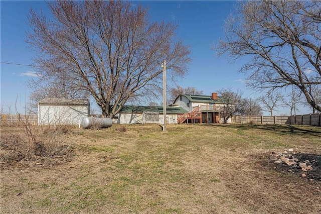 view of yard with a shed, a wooden deck, stairs, a fenced backyard, and an outbuilding