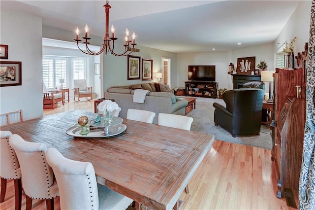 dining area with light hardwood / wood-style floors and an inviting chandelier