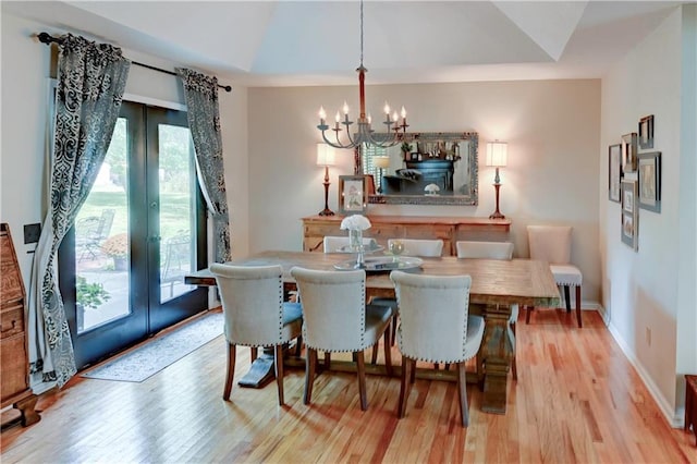 dining space with french doors, an inviting chandelier, light hardwood / wood-style flooring, and vaulted ceiling