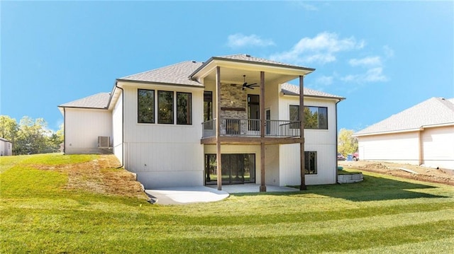 rear view of house featuring ceiling fan, a patio area, and a lawn