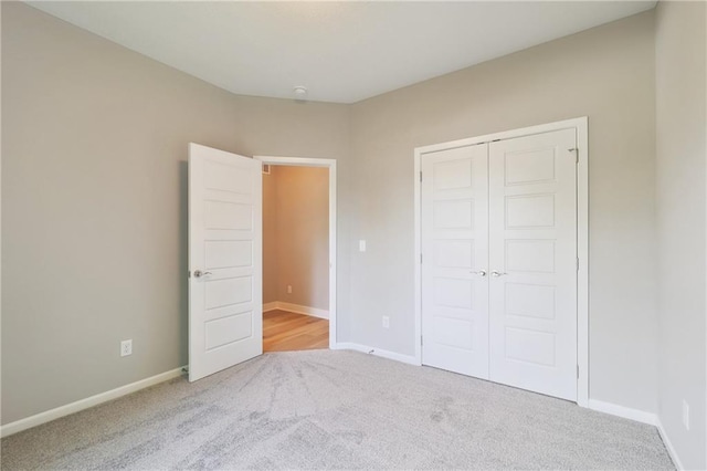 unfurnished bedroom featuring light colored carpet and a closet