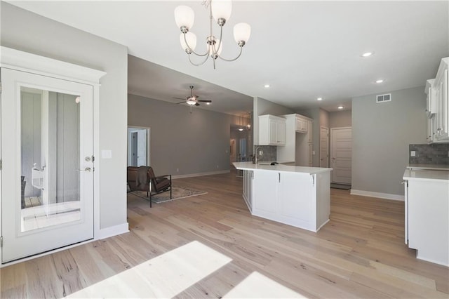 kitchen with light hardwood / wood-style flooring, backsplash, white cabinetry, and hanging light fixtures