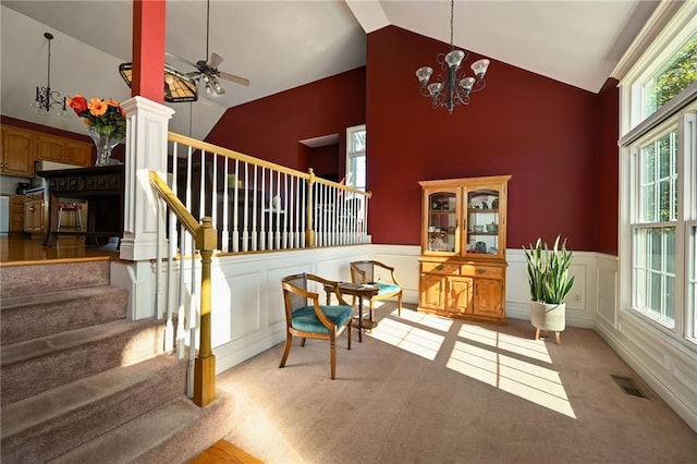 living area with ceiling fan with notable chandelier, carpet, and high vaulted ceiling