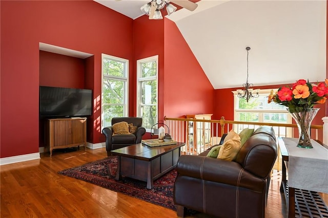 living room with ceiling fan with notable chandelier, plenty of natural light, dark hardwood / wood-style floors, and high vaulted ceiling