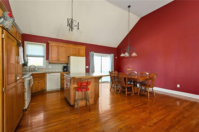 kitchen featuring a chandelier, a center island, dark hardwood / wood-style floors, high vaulted ceiling, and white appliances