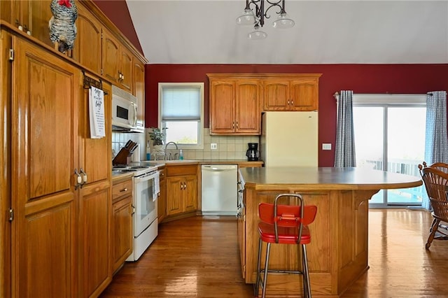 kitchen featuring white appliances, a chandelier, plenty of natural light, and a kitchen island