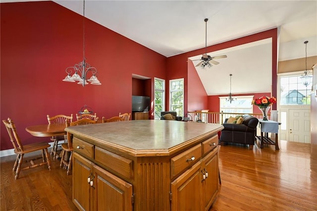 kitchen featuring decorative light fixtures, ceiling fan with notable chandelier, light wood-type flooring, and a center island