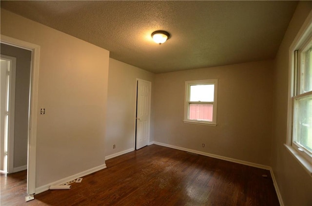 unfurnished room with dark wood-type flooring and a textured ceiling