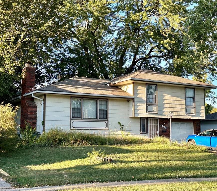 tri-level home with a garage and a front lawn