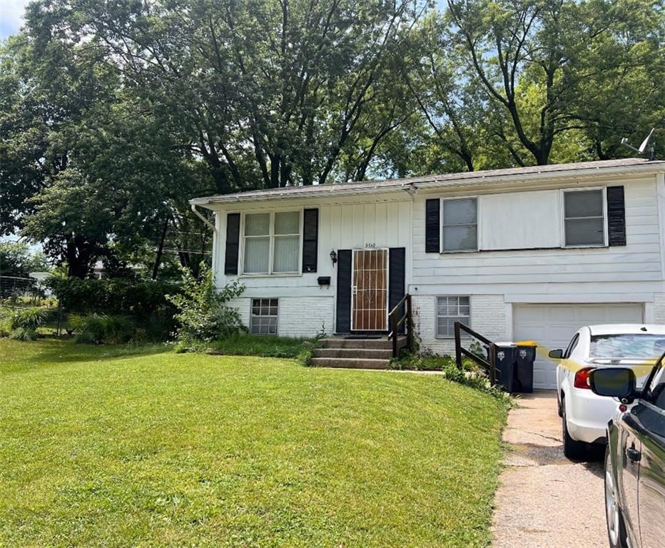 bi-level home featuring a garage and a front lawn