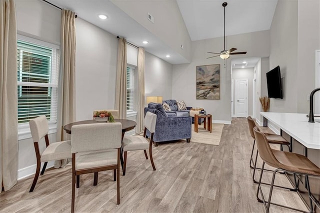 5830 Hunter Ct, Raytown, MO 64133 - dining space with baseboards, light wood-style floors, visible vents, ceiling fan, and high vaulted ceiling