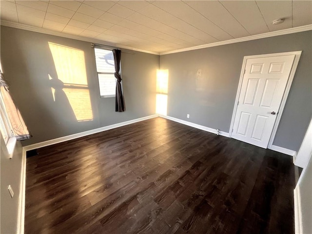 spare room with crown molding and dark wood-type flooring